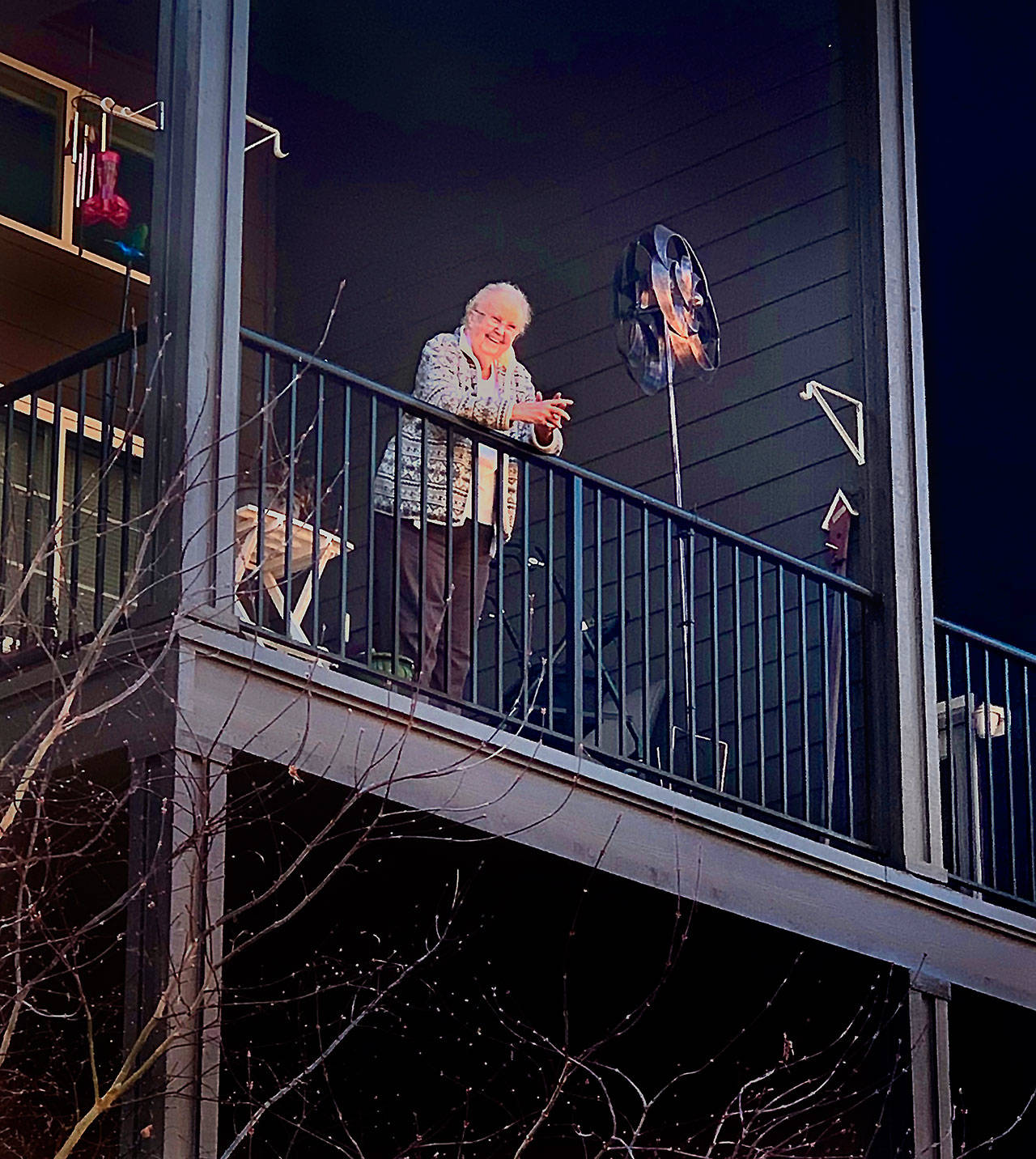 Carolyn Ross, on the balcony of her apartment at Arlington’s Olympic Place, is happily surprised on her 96th birthday Monday. Unable to visit the senior community due to coronavirus precautions, her children and their spouses sang “Happy Birthday” from outside. (Vanessa Ross photo)