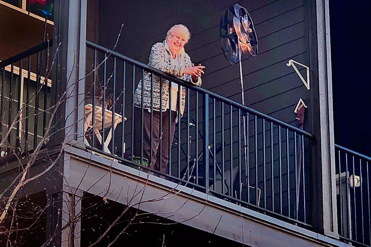 Carolyn Ross, on the balcony of her apartment at Arlington’s Olympic Place, is happily surprised on her 96th birthday Monday. Unable to visit the senior community due to coronavirus precautions, her children and their spouses sang “Happy Birthday” from outside. (Vanessa Ross photo)