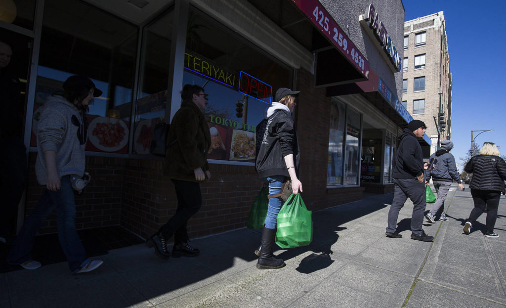 A Funko employee carries takeout meals as the group leaves the Tokyo Teriyaki restaurant in downtown Everett on Monday. (Andy Bronson / The Herald)
