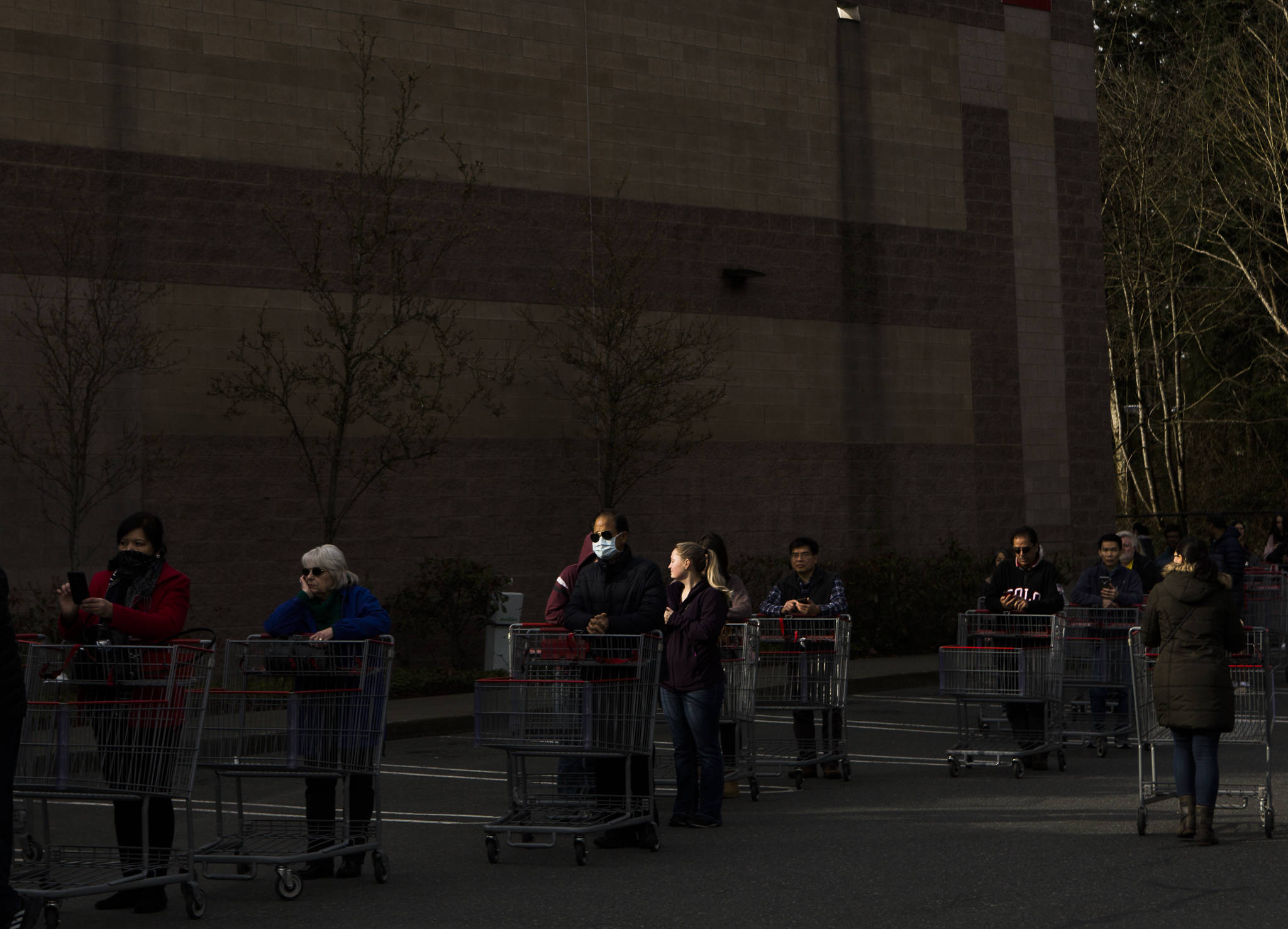 A man with a mask stands in line with hundreds of other shoppers waiting for Costco to open on Tuesday in Everett. (Olivia Vanni / The Herald)