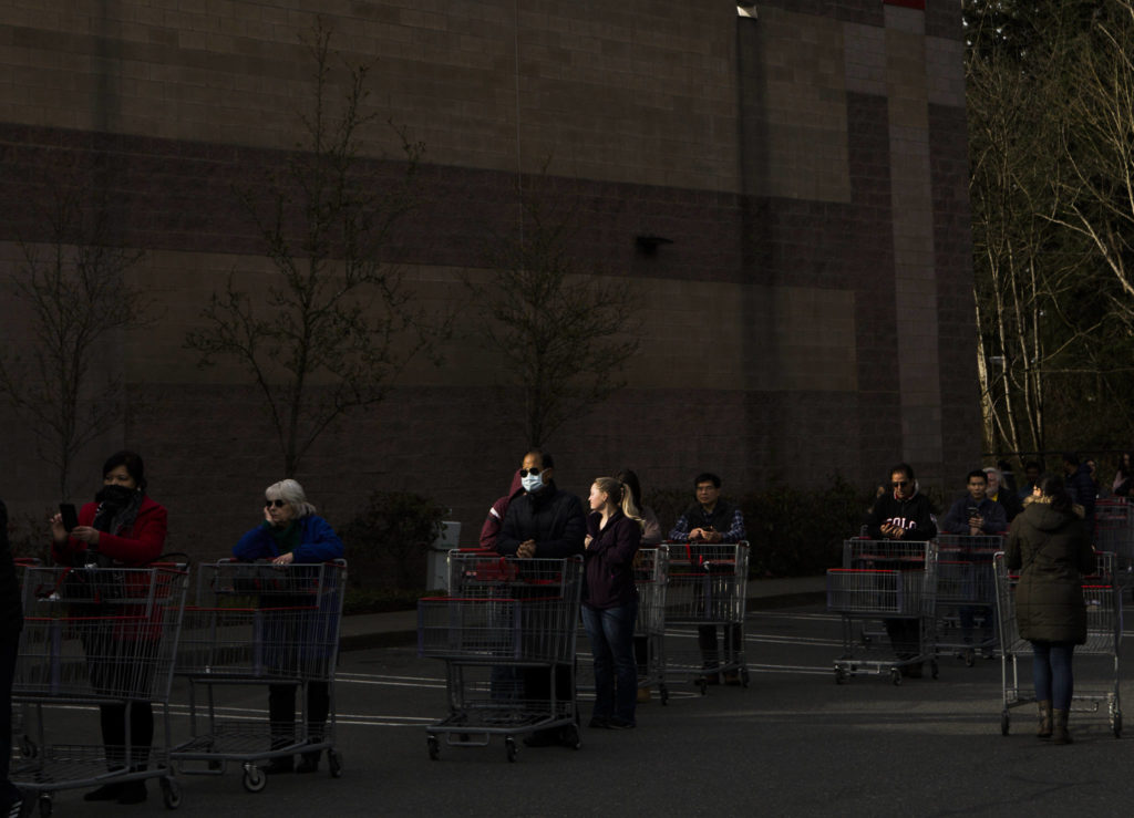 A man with a mask stands in line with hundreds of other shoppers waiting for Costco to open on March 17 in Everett. (Olivia Vanni / The Herald)
