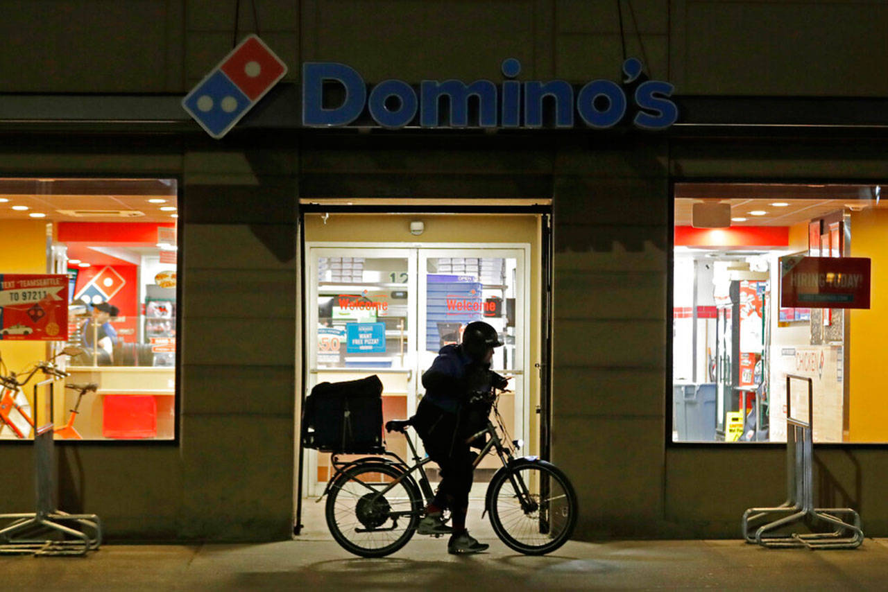 A delivery driver leaves a Domino’s Pizza restaurant in downtown Seattle on a bike, Sunday. Gov. Jay Inslee said Sunday night he would order all bars, restaurants, entertainment and recreation facilities in the state to temporarily close to fight the spread of the Covid-19 coronavirus. Inslee said that restaurants could continue take-out and delivery services. (Ted S. Warren / Associated Press)