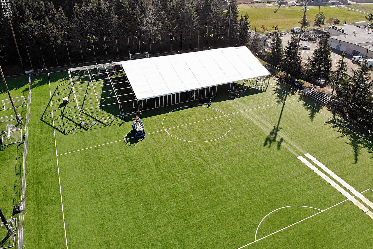 Workers erect a temporary field hospital for use by people unable to isolate and recover from COVID-19 in their own homes on a soccer field Thursday in Shoreline. (AP Photo/Elaine Thompson)