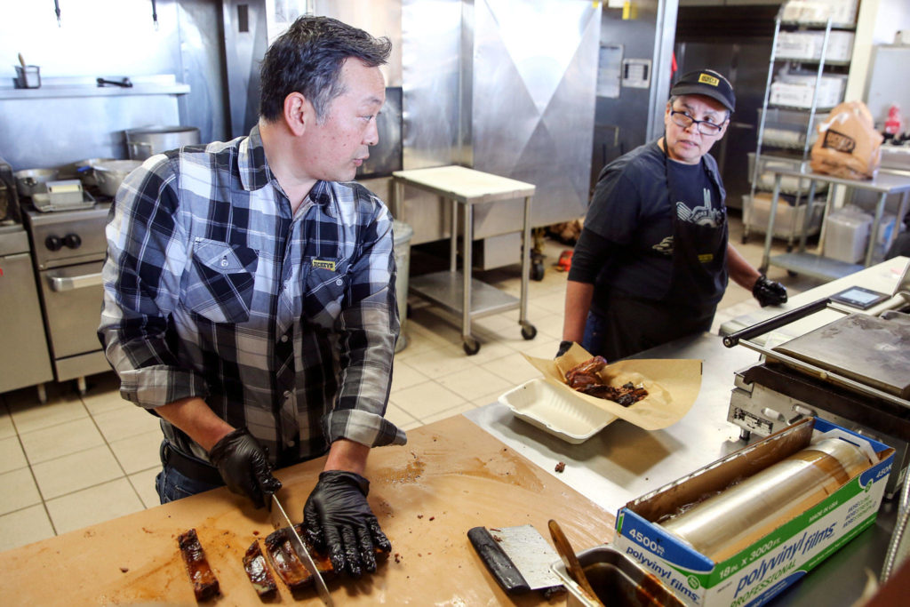 Owner Chad Manivanh works with Martha Escobar at Dickey’s Barbecue Pit in Everett on March 20. “People are ordering online and picking up and leaving very generous tips,” Manivanh says. “People are amazing!” (Kevin Clark / The Herald)
