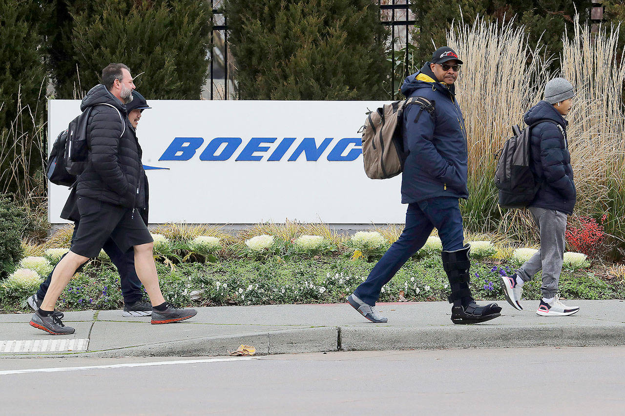 This December 2019 photo shows workers walking past a Boeing Co. sign as they leave the factory where the company’s 737 Max airplanes are built in Renton. (AP Photo/Ted S. Warren, file)