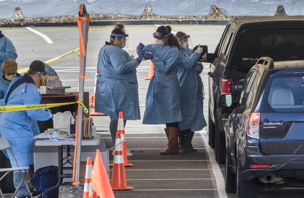 A medical worker gives a thumbs up as two others collect a coronavirus test swab on Monday, in a parking lot near Everett Memorial Stadium. Each test is free and by appointment only, for those who meet a certain criteria. (Andy Bronson / The Herald)
