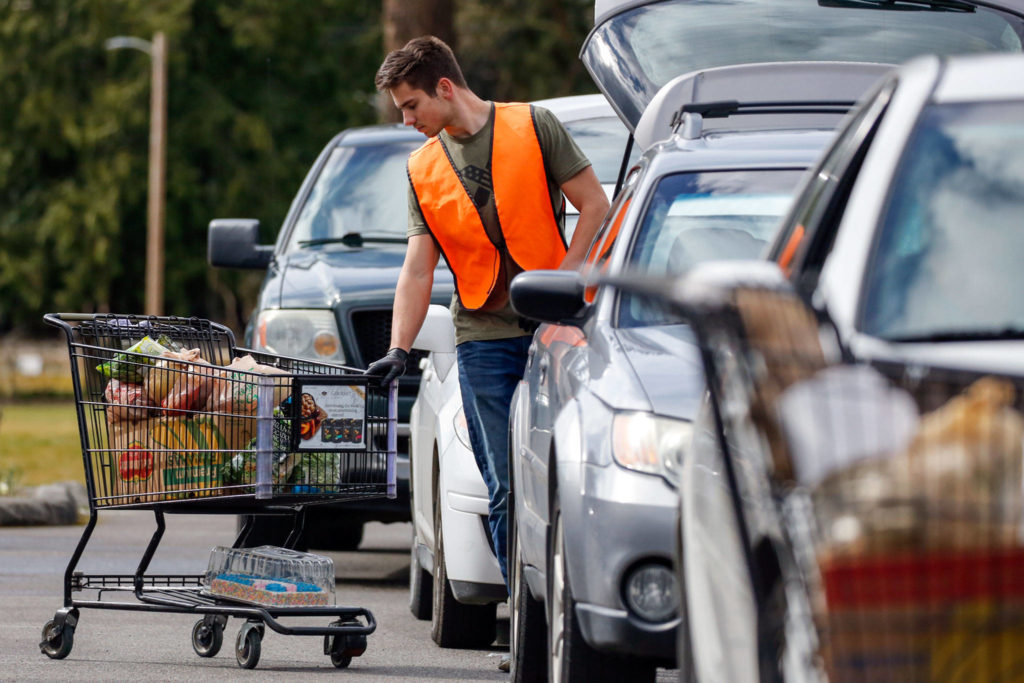 Dominic Andrews loads food stuffs to a customer’s car Tuesday afternoon at Marysville Community Food Bank. (Kevin Clark / The Herald)
