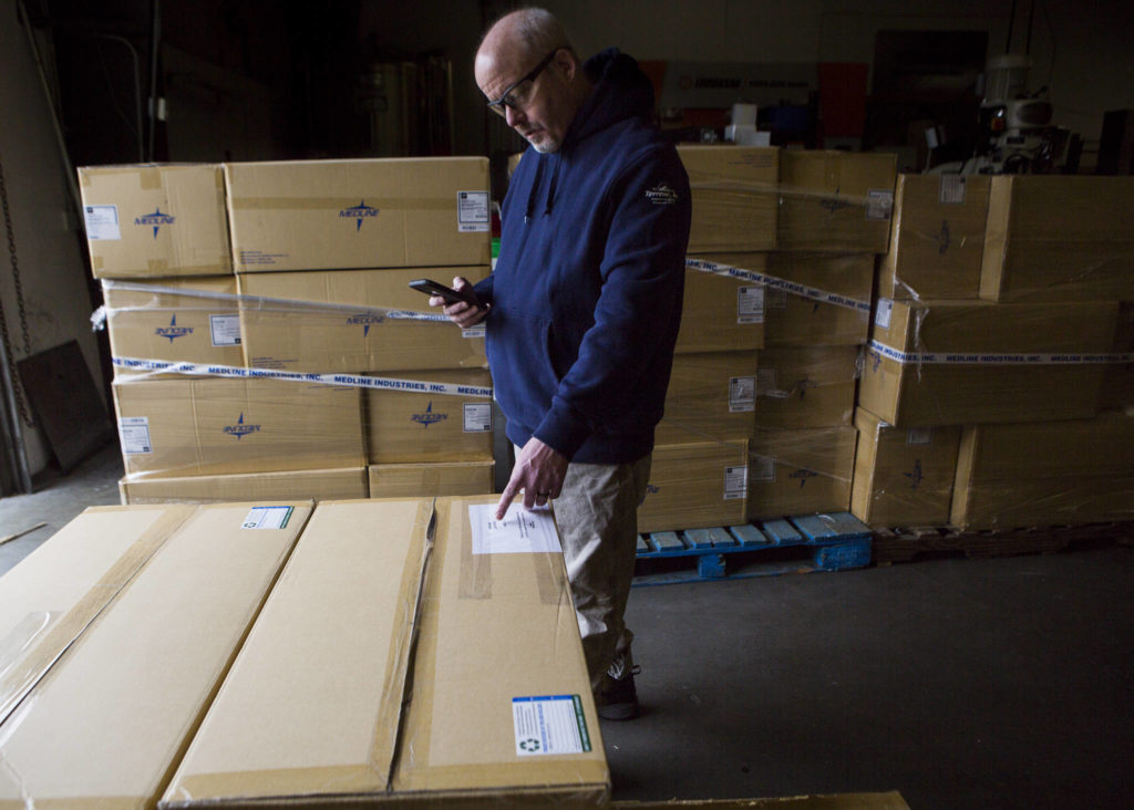 Colin Chadwick calculates how many mask kits are being sent to Kaas Tailored each day from Terrene Inc. on Friday in Mukilteo. (Olivia Vanni / The Herald)
