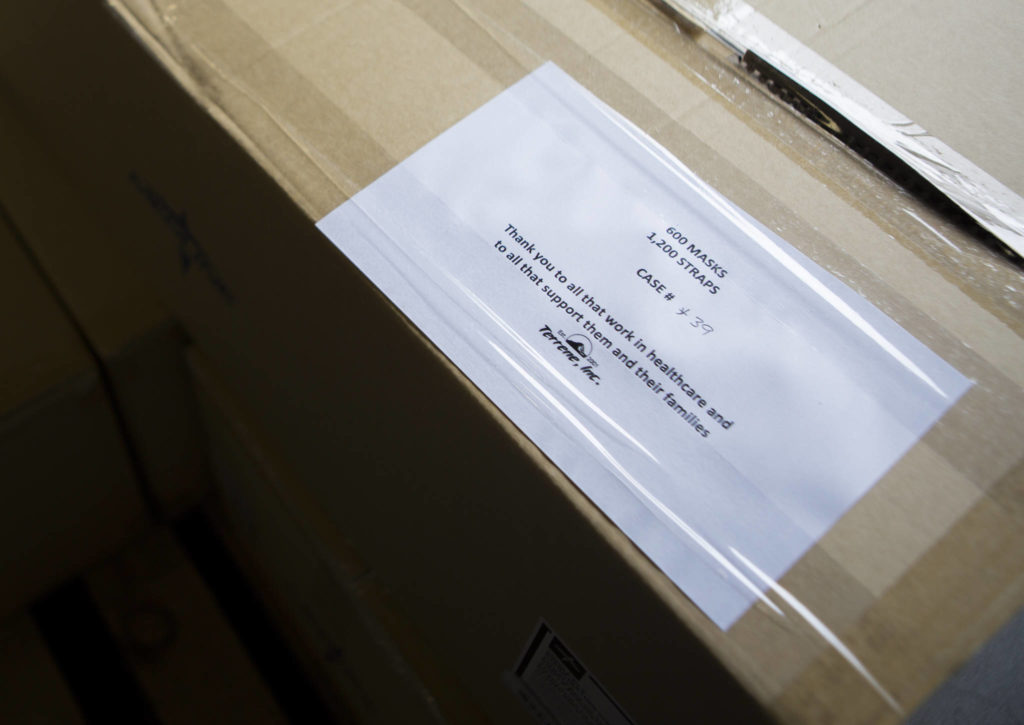A case-number sheet, along with a note thanking health care workers, is taped to a mask kit for transfer at Terrene Inc. on Friday in Mukilteo. (Olivia Vanni / The Herald) 
