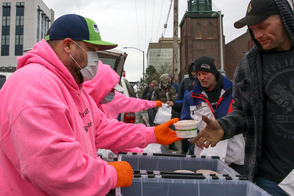 Members of the The Hand Up Project distribute meals in downtown Everett Thursday afternoon. (Kevin Clark / The Herald)
