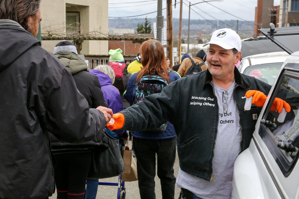 Robert Smiley of The Hand Up Project hands out hand sanitizer in downtown Everett Thursday afternoon. (Kevin Clark / The Herald) 
