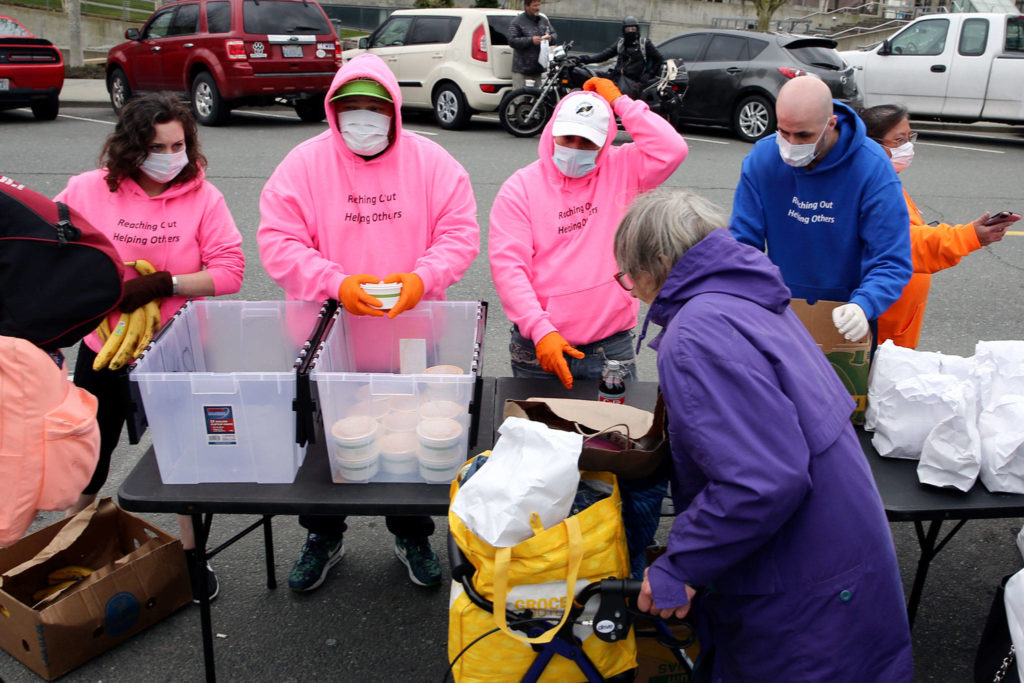 Members of the The Hand Up Project distribute meals in downtown Everett Thursday afternoon. (Kevin Clark / The Herald)
