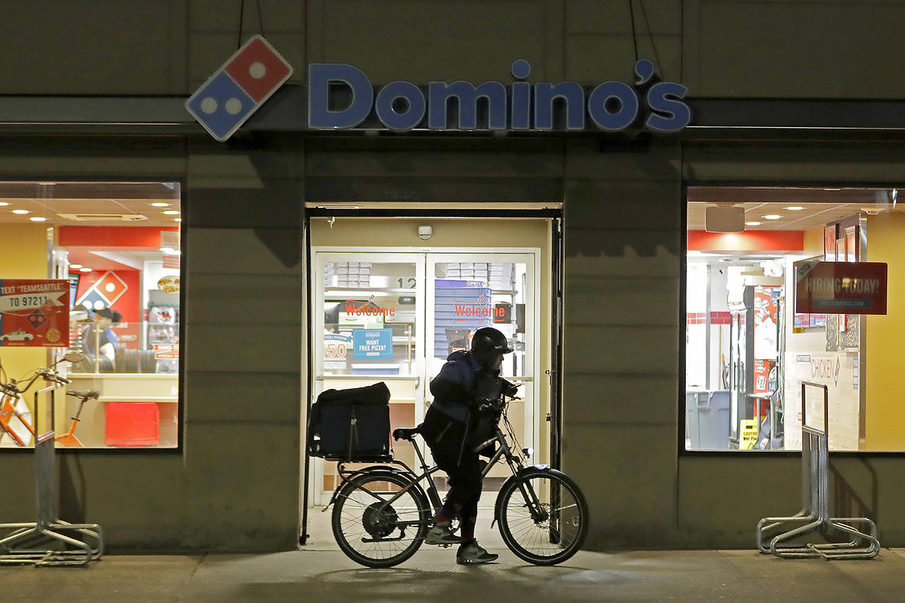 A delivery driver leaves a Domino’s Pizza restaurant in downtown Seattle on a bike Sunday. (AP Photo/Ted S. Warren)