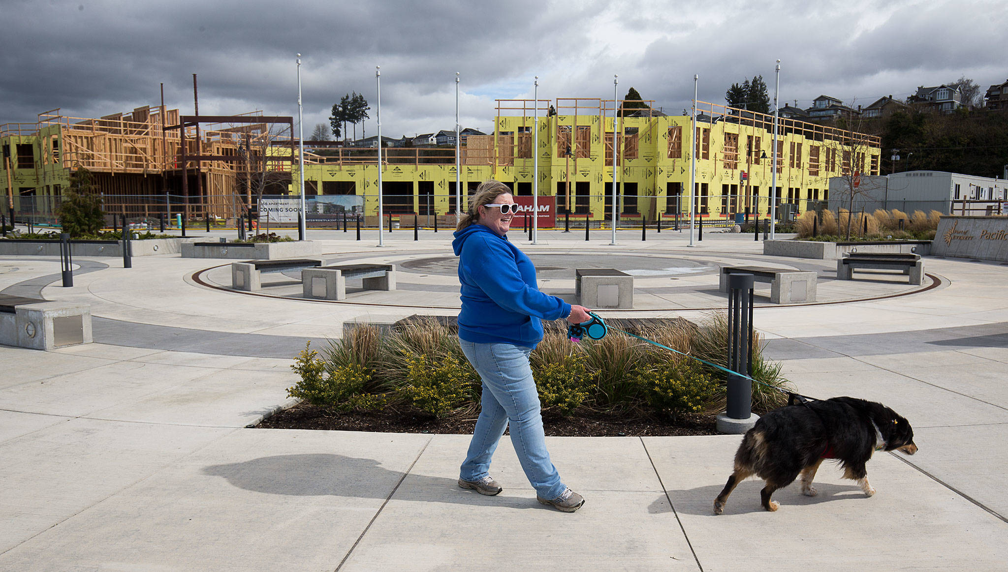 Amy Ulrich walks her dog, Kahlua, by the Waterfront Place Apartments at the Port of Everett on Monday. Gov. Jay Inslee ordered most construction projects around the state to shut down for two weeks. That paused work at several big housing projects, including this one at the port. (Andy Bronson / The Herald)