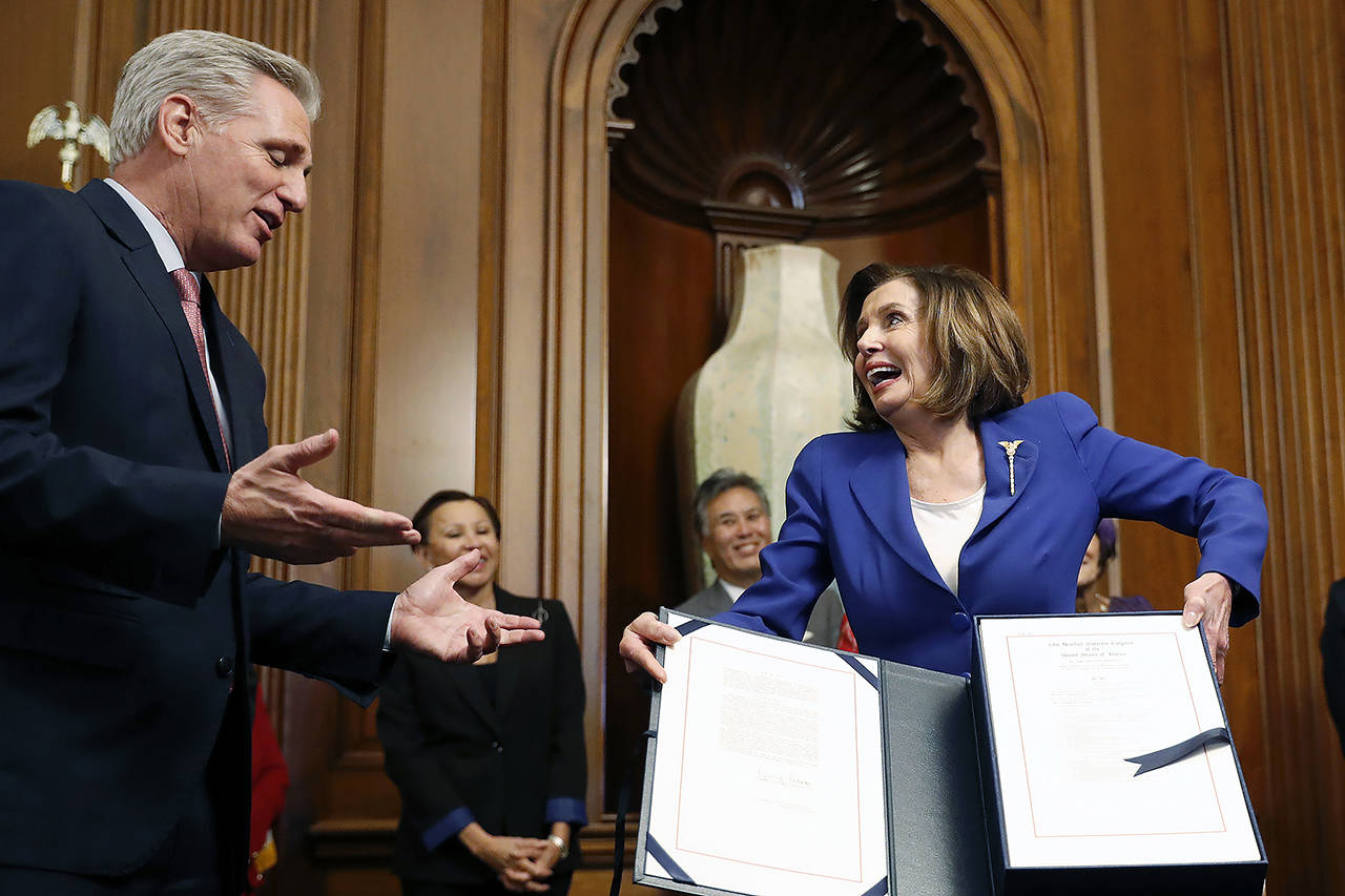House Speaker Nancy Pelosi, accompanied by House Minority Leader Kevin McCarthy and other legislators, participate in a bill enrollment ceremony for the Coronavirus Aid, Relief, and Economic Security (CARES) Act, after it passed in the House, on Capitol Hill on Friday. (AP Photo/Andrew Harnik)