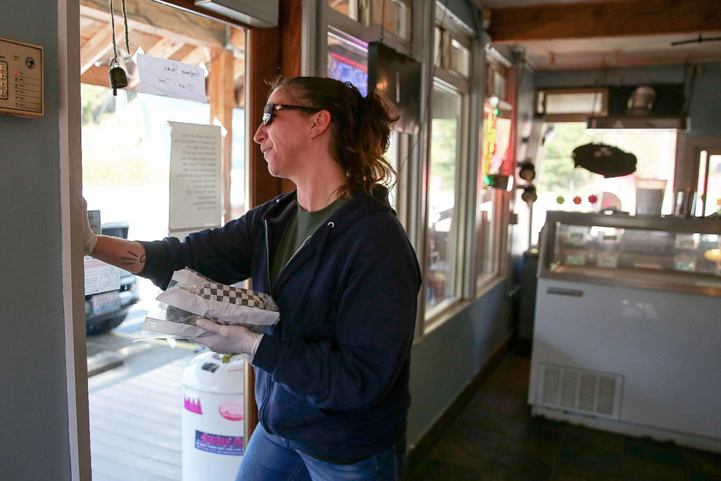 Dee Hatch delivers a food order to a waiting customer at Sky Deli. (Kevin Clark / The Herald)
