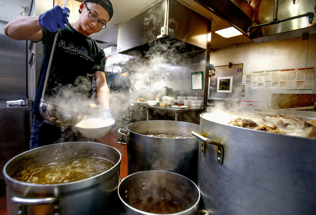 In the aromatic kitchen of Basil Authentic Vietnamese Cuisine, cook Dung Pham appears and occasionally disappears in the mist rising above giant pots filled with hot broth. (Dan Bates / The The Herald)
