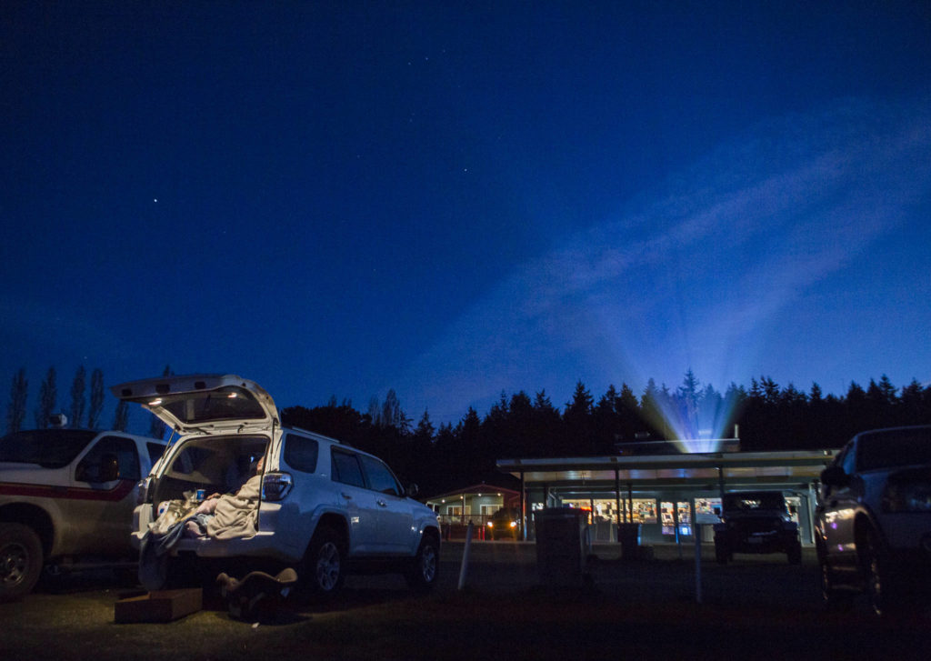 People bundle up in blankets in their cars as the first movie of a double feature, Disney’s “Onward,” begins to play at the Blue Fox Drive-In on March 19 in Oak Harbor. The drive-in had more than 85 cars that night. (Olivia Vanni / The Herald)
