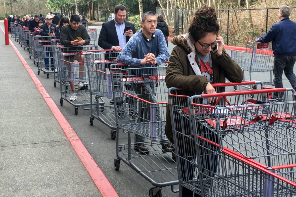 Customers wait in a line wrapped around the building at Costco in Everett on March 17. The wholesale retailer was only allowing 30 people in at a time. (Kevin Clark / The Herald)
