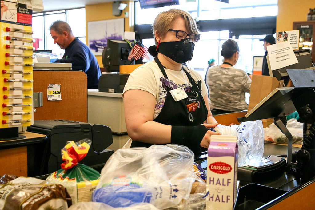 Dani Pratt checks out groceries for a customer at QFC in Everett on March 25. (Kevin Clark / The Herald)
