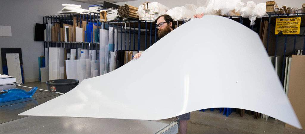 Store Manager Ben Winslow cuts sheets of plastic for customers’ orders at Tap Plastics on Monday in Everett. The cut sheets will be made into sneeze guards and face masks. (Andy Bronson / The Herald)
