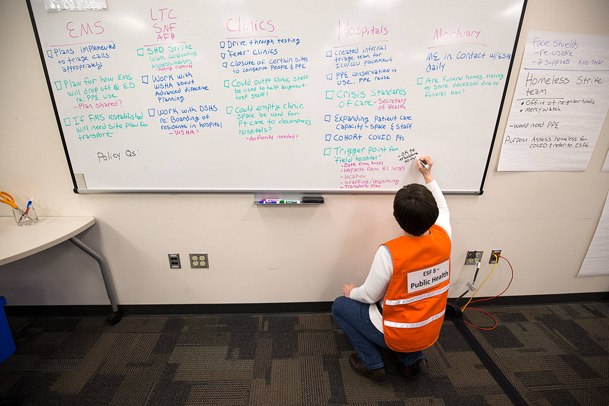 Assistant Director of Prevenetion Services Katie Curtis makes lists on a whiteboard in a room at the Snohomish County Emergency Management Center on March 30 in Everett. (Andy Bronson / The Herald)