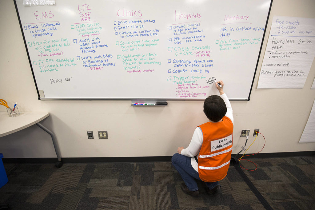 Assistant Director of Prevention Services Katie Curtis makes lists on a whiteboard in a room at the Snohomish County Emergency Management Center on March 30 in Everett. (Andy Bronson / The Herald)
