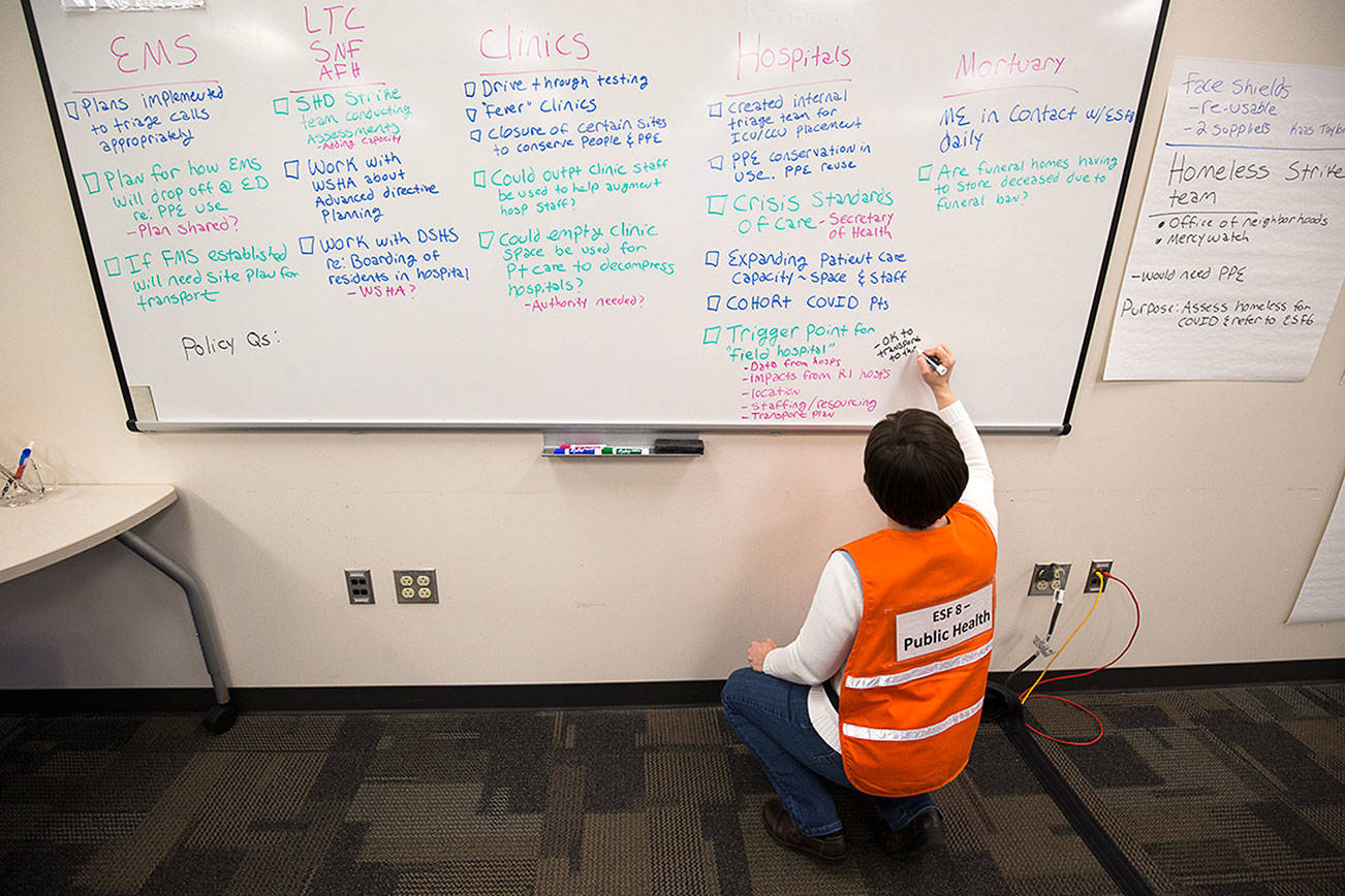 Assistant Director of Prevention Services Katie Curtis makes lists on a whiteboard in a room at the Snohomish County Emergency Management Center on March 30 in Everett. (Andy Bronson / The Herald)