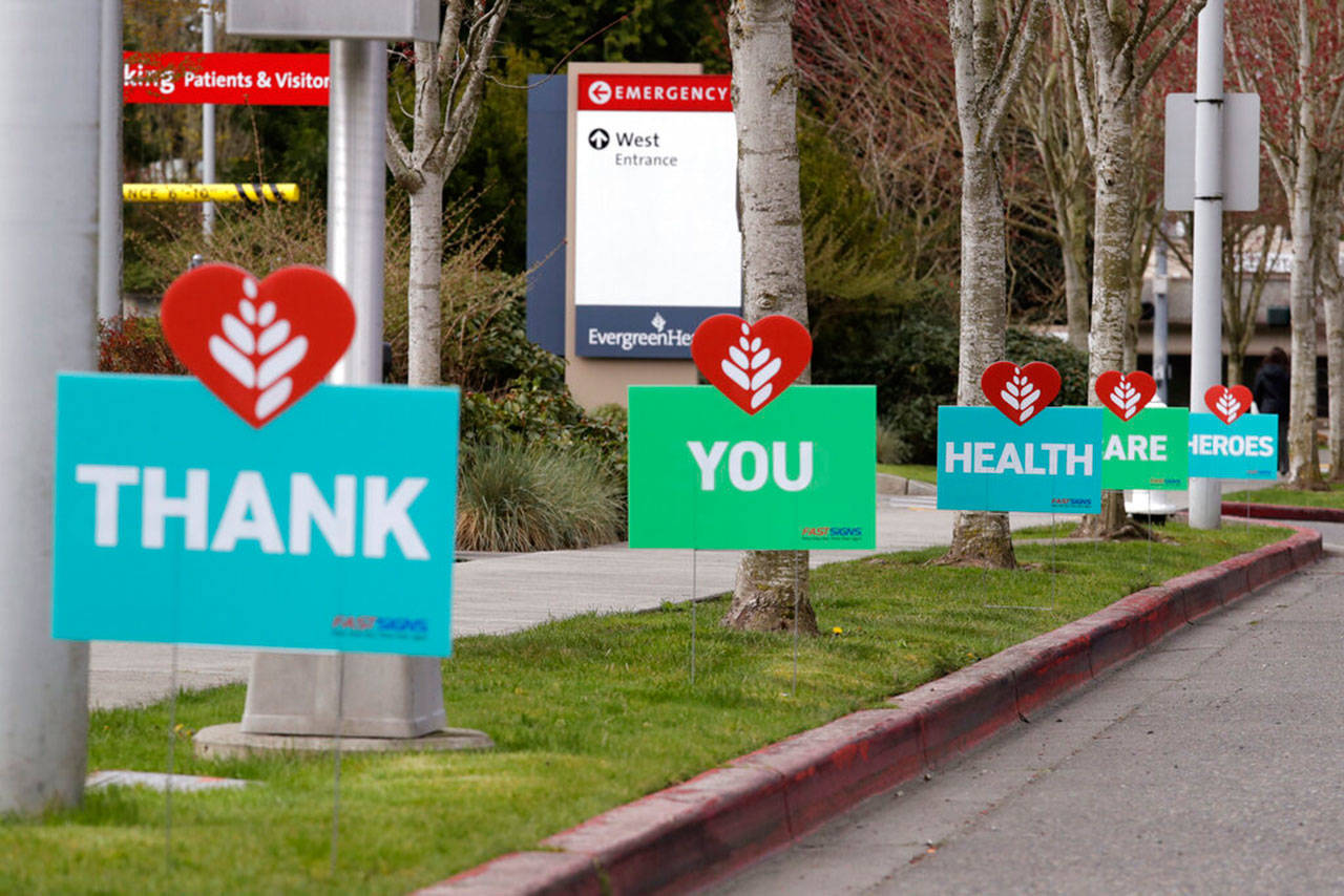 A line of signs in appreciation of health care employees working during the coronavirus outbreak line the curb in front of EvergreenHealth Medical Center on Thursday, in Kirkland. (Elaine Thompson / Associated Press)