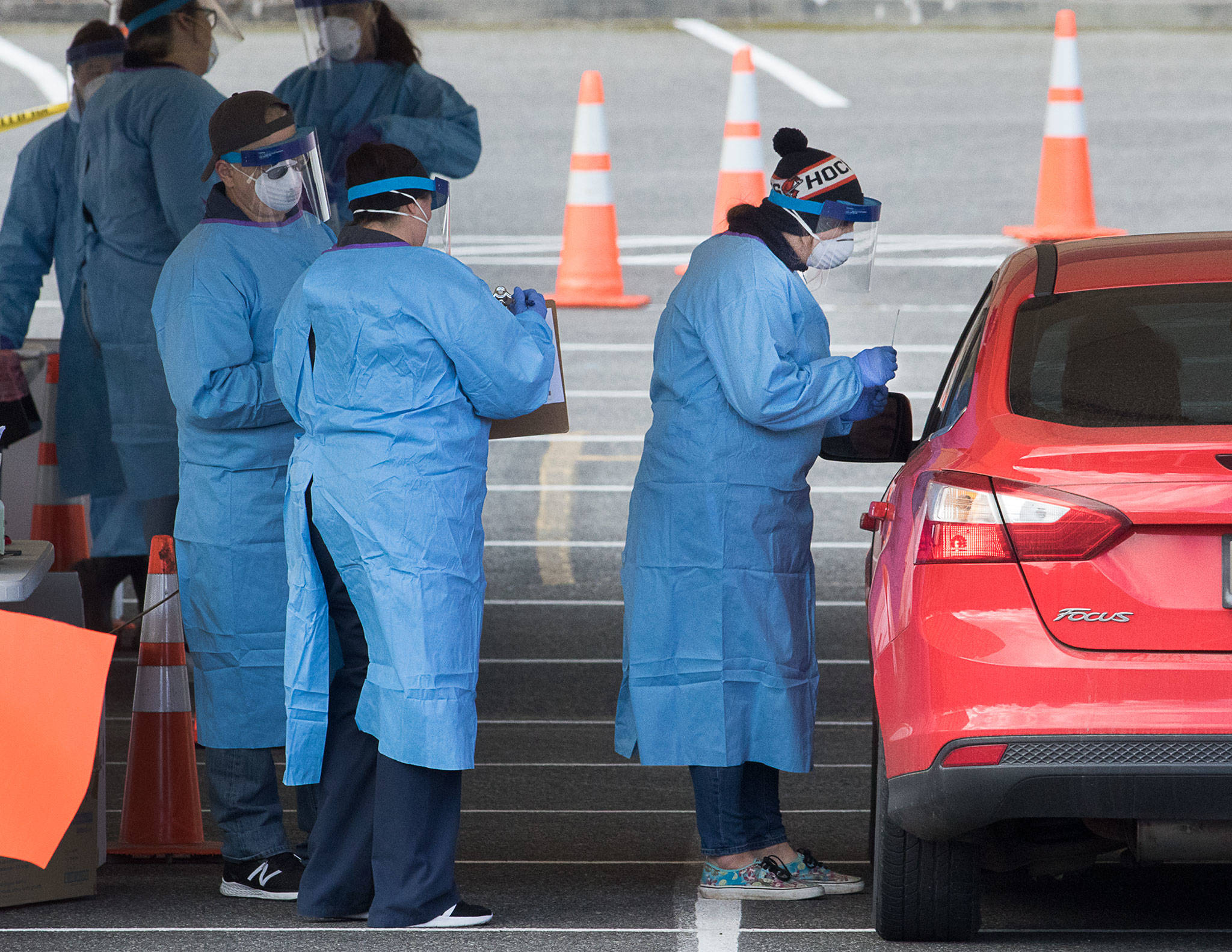 Medical workers test for the COVID-19 virus at a drive-thru testing site in the parking lot near Everett Memorial Stadium at 3900 Broadway on Monday in Everett. Only patients with referrals from a doctor are tested, after setting up an appointment. (Andy Bronson / The Herald)