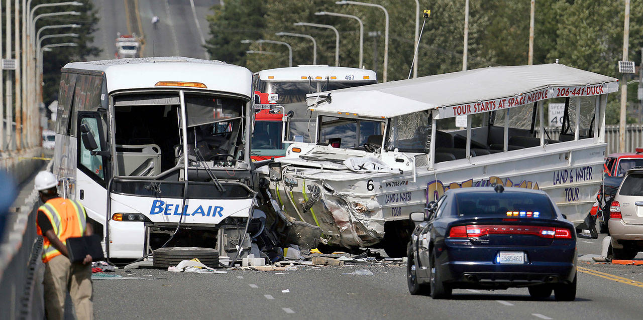 In this Sept. 24, 2015 photo, a “Ride the Ducks” amphibious tour bus (right) and a charter bus remain at the scene of a multiple fatality collision on the Aurora Bridge in Seattle. (AP Photo/Elaine Thompson, File)