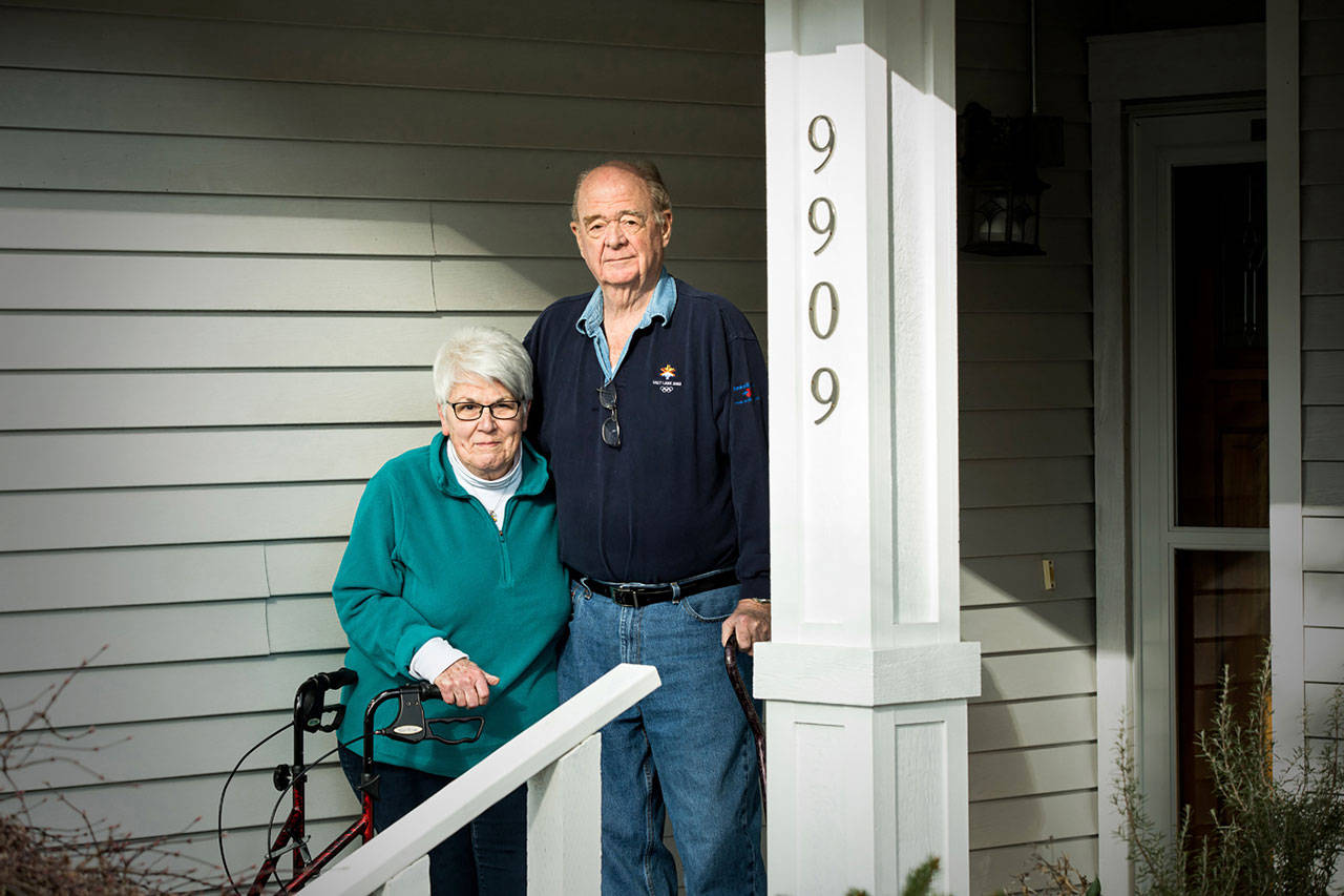 Josie and George Taylor stand on the porch of their home in Everett on March 24. They both fell ill in early March and ended up at EvergreenHealth medical center with COVID-19, before deciding to join a clinical trial for an experimental drug. (Dan DeLong/Kaiser Health News)