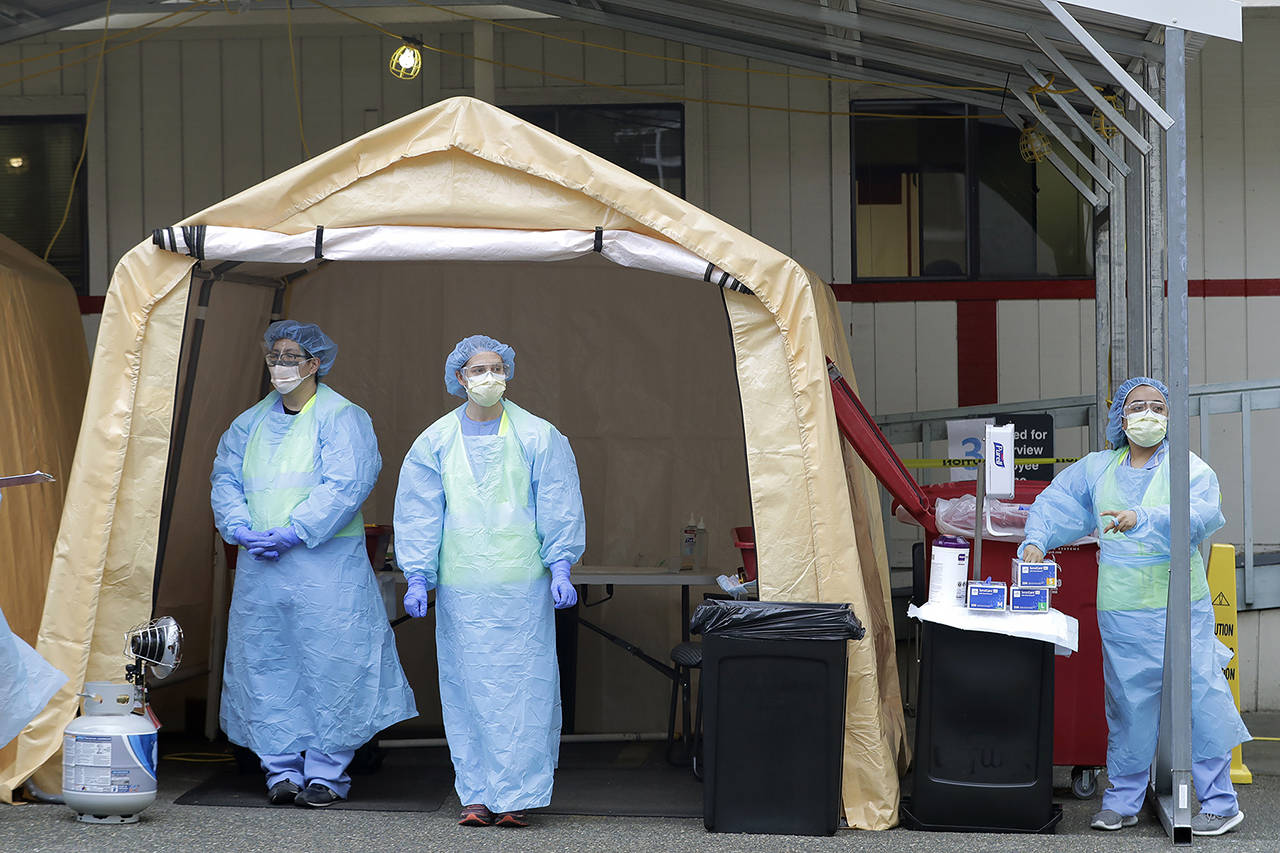 Nurses wait for cars at a drive-up coronavirus testing station at Harborview Medical Center hospital on Thursday in Seattle. (AP Photo/Ted S. Warren)