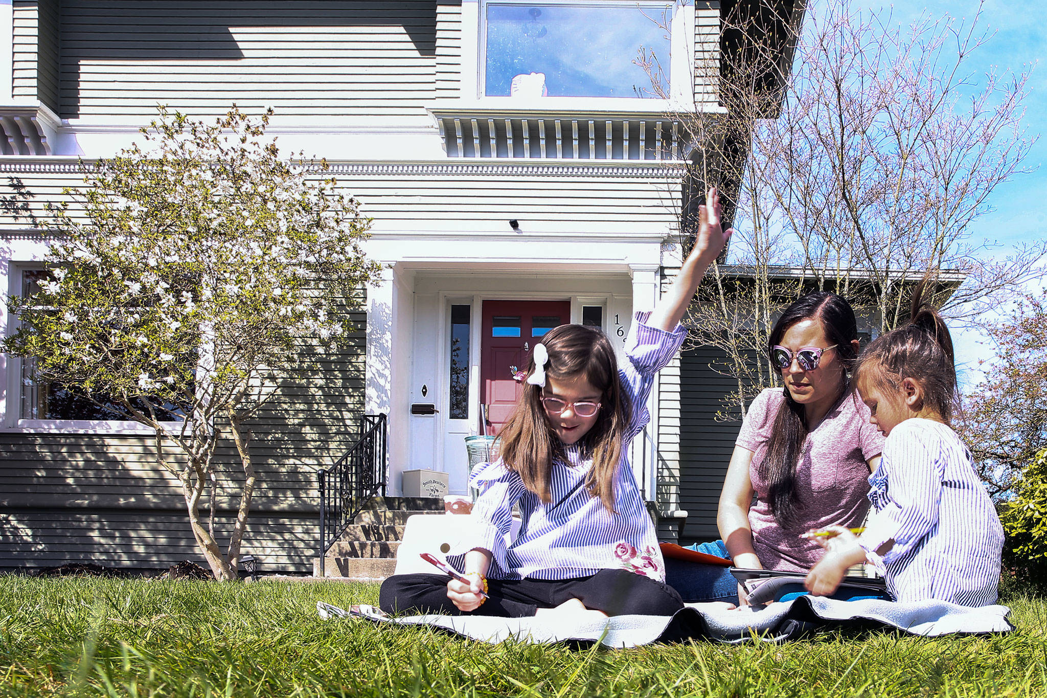 Paige Bone, 7, (left to right), celebrates finishing her timed math assignment with mother Aisha Bone and sister Poppy Bone looking on Friday morning at their home in Everett on April 17, 2020. (Kevin Clark / The Herald)