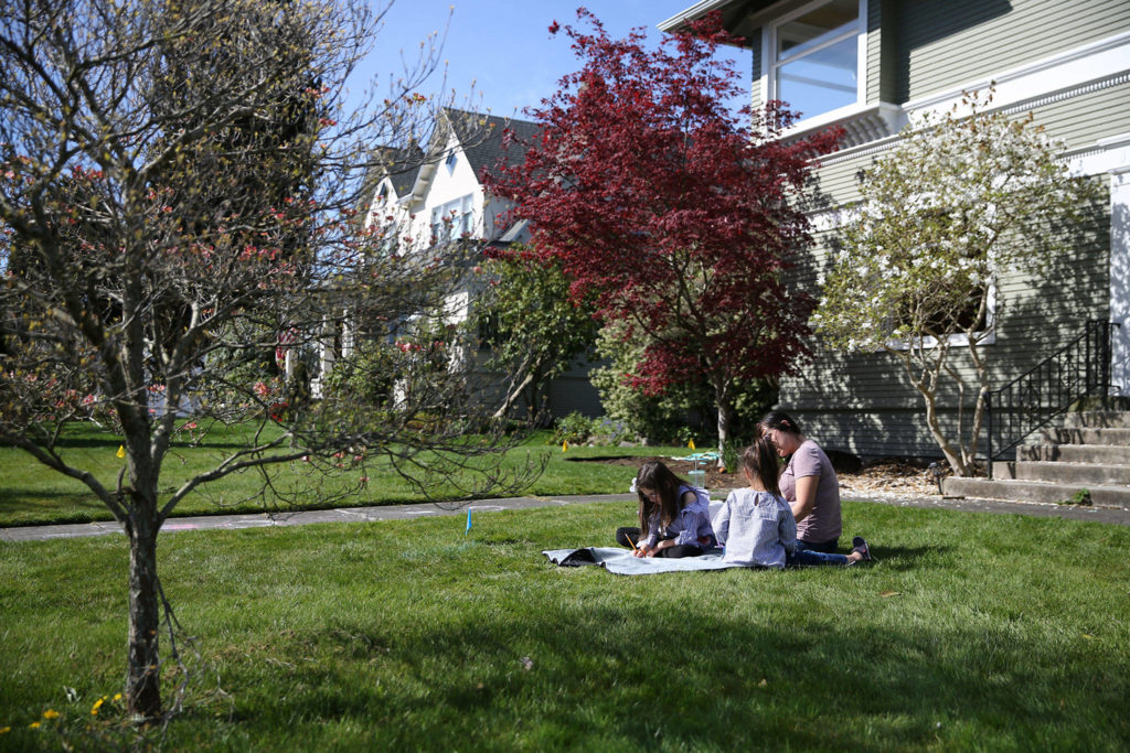 Paige Bone (left-right) Poppy Bone and Aisha Bone work through school assignments Friday morning at their home in Everett on April 17, 2020. (Kevin Clark / The Herald)
