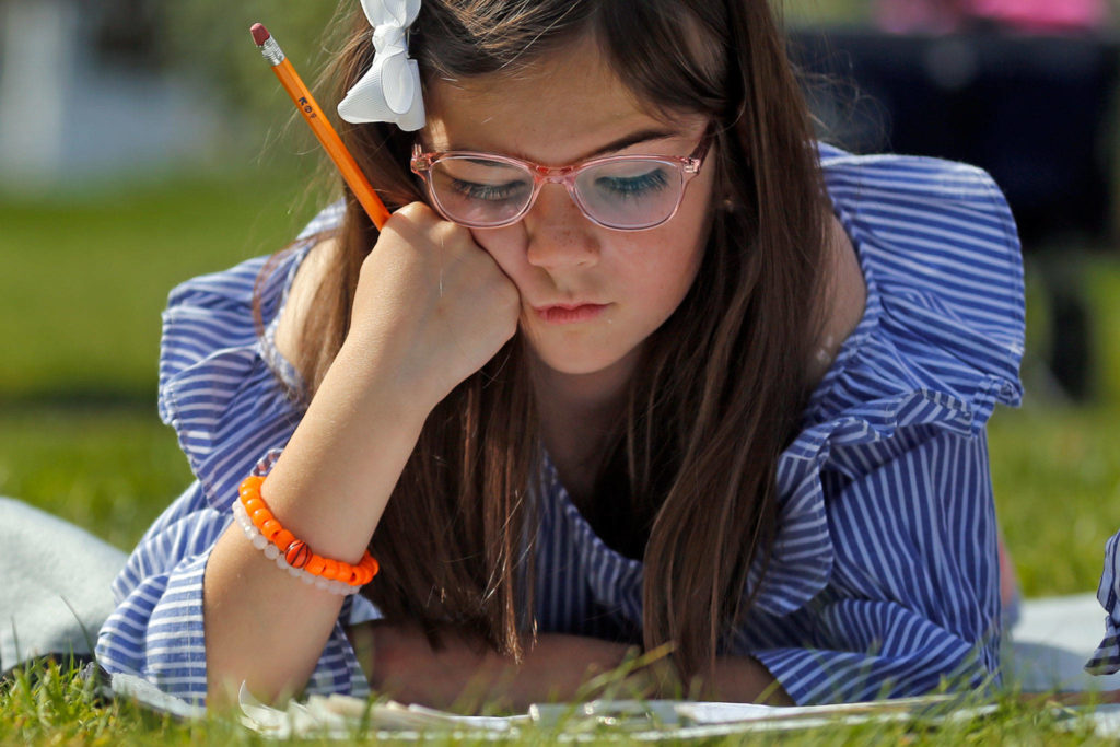 Paige Bone, 7, works through an assignment Friday morning at their home in Everett on April 17, 2020. (Kevin Clark / The Herald)
