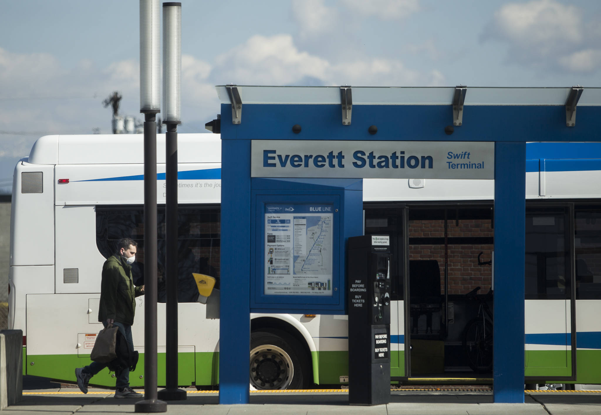 A man wearing a face mask walks toward the rear entrance of a Community Transit bus at the Everett Station on Friday, March 20, 2020 in Everett, Wa. (Olivia Vanni / The Herald)