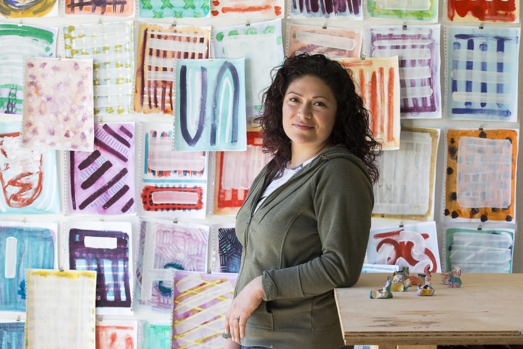 Artist Cat Snapp in her Everett studio on April 13, surrounded by her recent abstract works, including mixed-media on paper and small sculptures made of clay. (Andy Bronson / The Herald)
