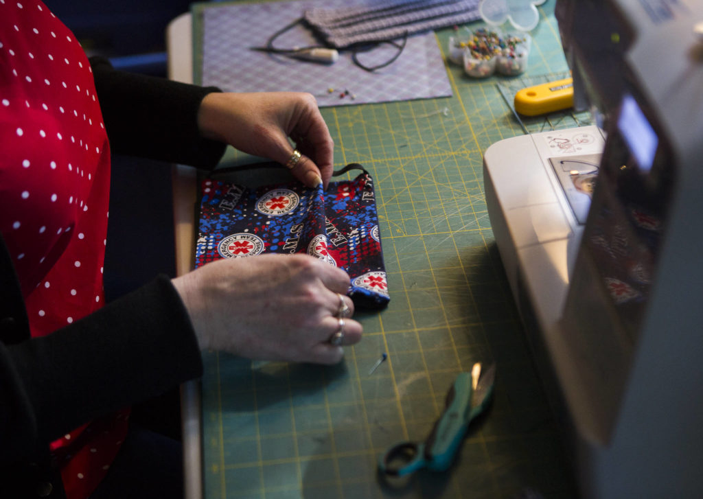 Nikki Speaks folds emergency response themed fabric for a mask on April 10 in Woodinville. (Olivia Vanni / The Herald)
