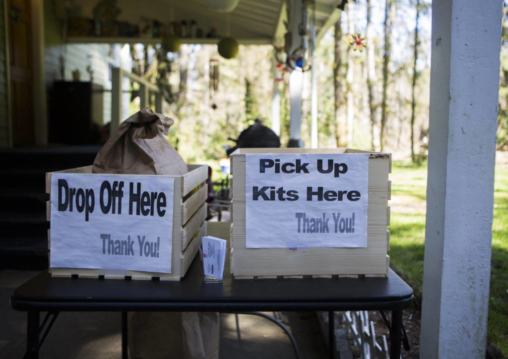 Two bins, one for drop off of finished masks, another for picking up mask kits, sit near the entrance of Nikki Speaks’ home on April 10 in Woodinville. (Olivia Vanni / The Herald)
