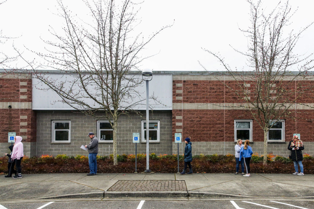 Parents and students wait outside Henry M. Jackson High School in Mill Creek in check out devices on March 18. (Kevin Clark / Herald file)
