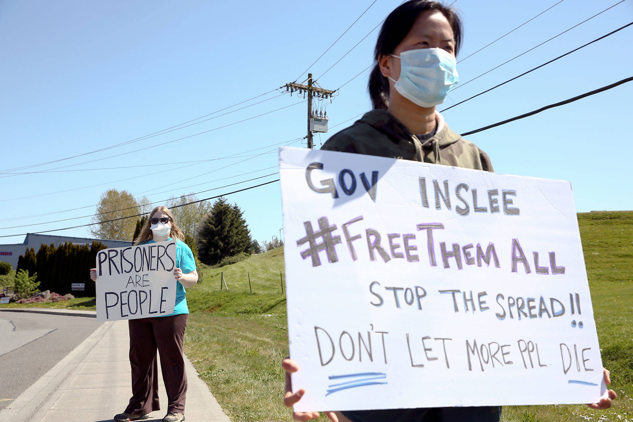 Masked protestors stand outside the grounds of the Monroe Correctional Complex in Monroe on Thursday. (Kevin Clark / The Herald)