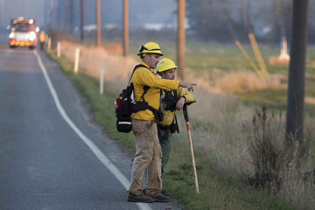 Two Department of Natural Resources firefighters keep watch on a section of fire as it heads toward Highway 9 on Wednesday in Bryant. (Andy Bronson / The Herald)
