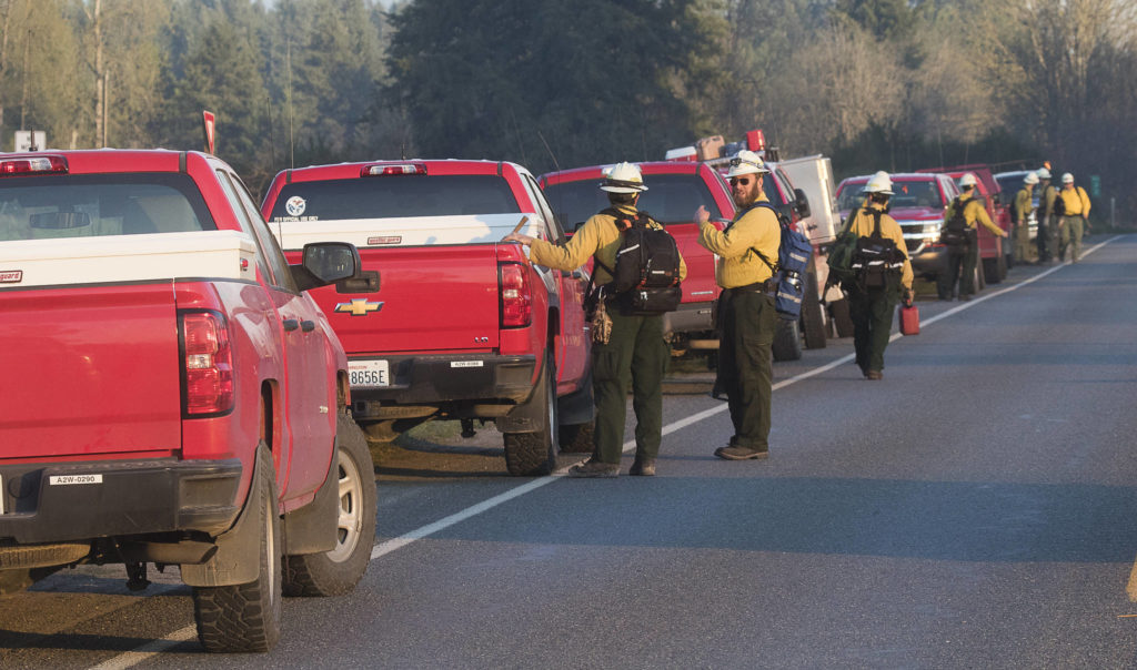 Trucks line Highway 9 as Department of Natural Resources firefighters head toward different areas of a brush fire Wednesday in Bryant. (Andy Bronson / The Herald)
