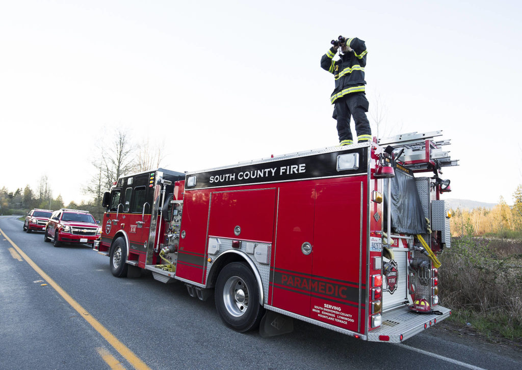 Jason Shield of South County Fire watches a fire as multiple strike teams from Snohomish County fire departments fight a large brush fire along Highway 9 on Wednesday in Bryant. (Andy Bronson / The Herald)
