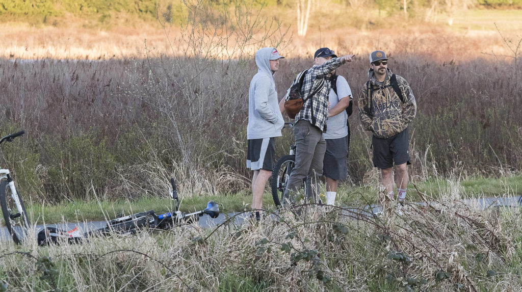 Bike riders watch from the Centennial Trail as multiple strike teams from Snohomish County fire departments fight a large brush fire along Highway 9 on Wednesday in Bryant. (Andy Bronson / The Herald)
