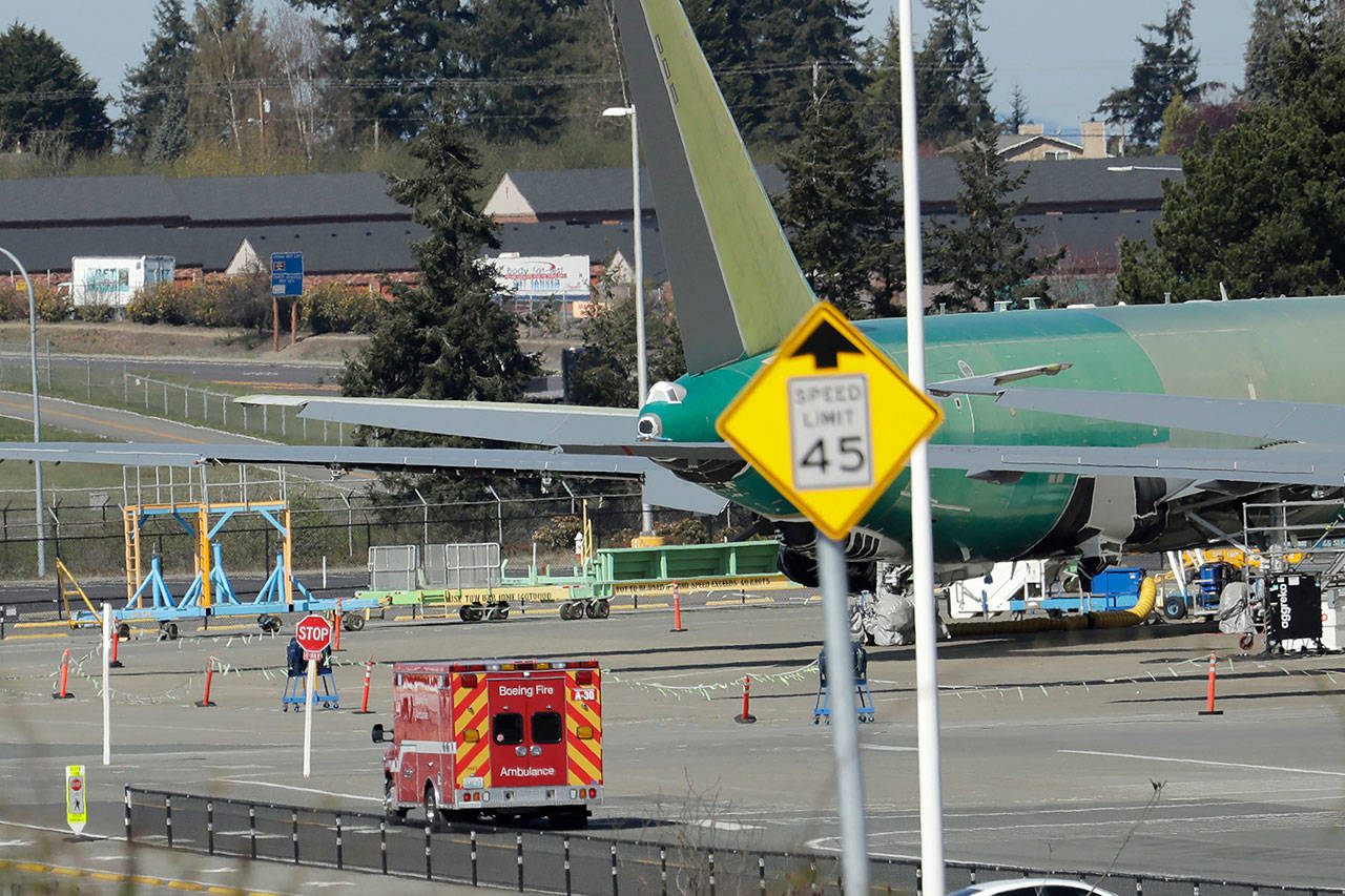 A Boeing Fire Dept. ambulance drives slowly past a U.S. Air Force KC-46 tanker being built by Boeing on Monday at Boeing’s airplane assembly facility in Everett. (AP Photo/Ted S. Warren)