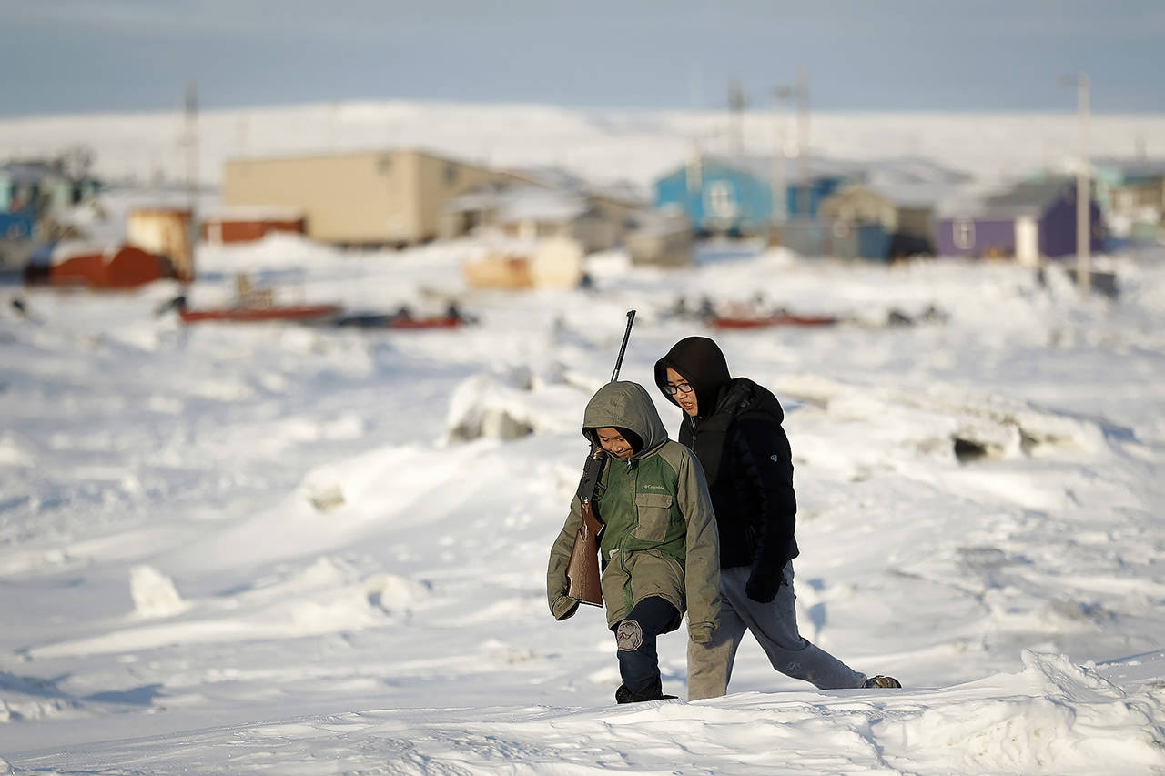 In this Jan. 18 photo, George Chakuchin (left) and Mick Chakuchin walk on ice over the Bering Sea in Toksook Bay, Alaska, a mostly Yuip’ik village. Native American leaders are raising questions about how $8 billion in federal coronavirus relief tagged for tribes will be distributed, with some arguing that for-profit Alaska Native corporations shouldn’t get a share of the funding. (AP Photo/Gregory Bull, File)