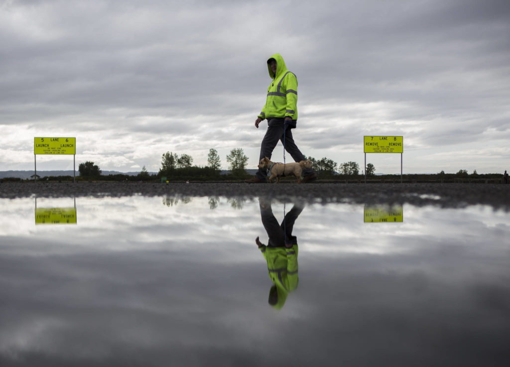 A man walks a dog past the 10th Street Boat Launch. (Olivia Vanni / The Herald)
