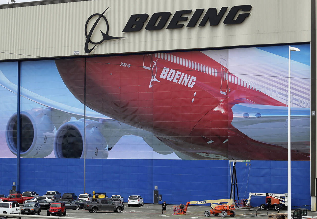 FILE - In this Monday, March 23, 2020, file photo, a worker walks near a mural of a Boeing 747-8 airplane at the company’s manufacturing facility in Everett. (AP Photo/Ted S. Warren, File)